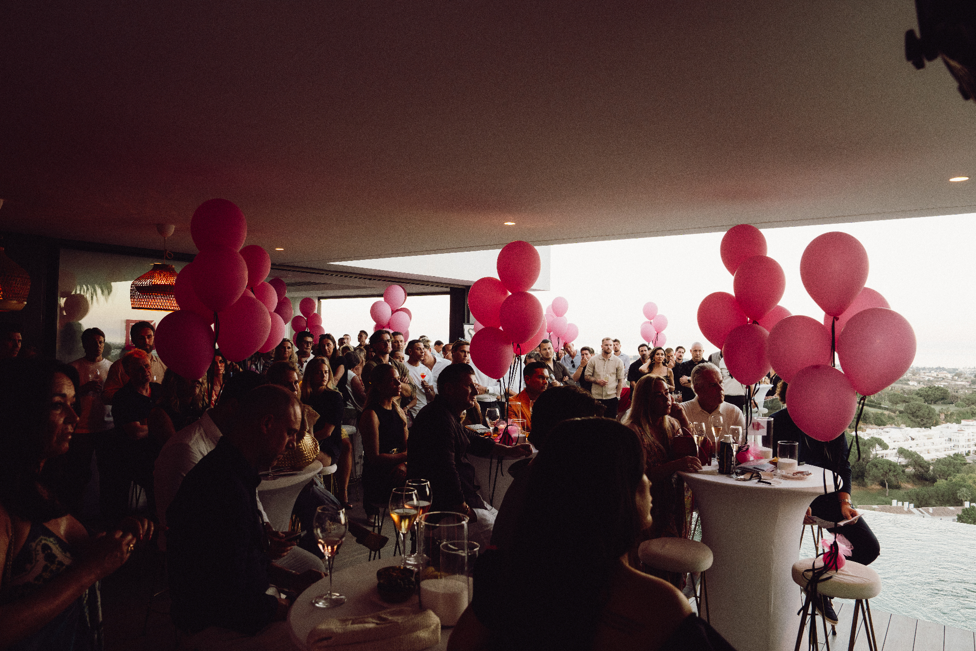 Audience at the charity night surrounded by pink balloons
